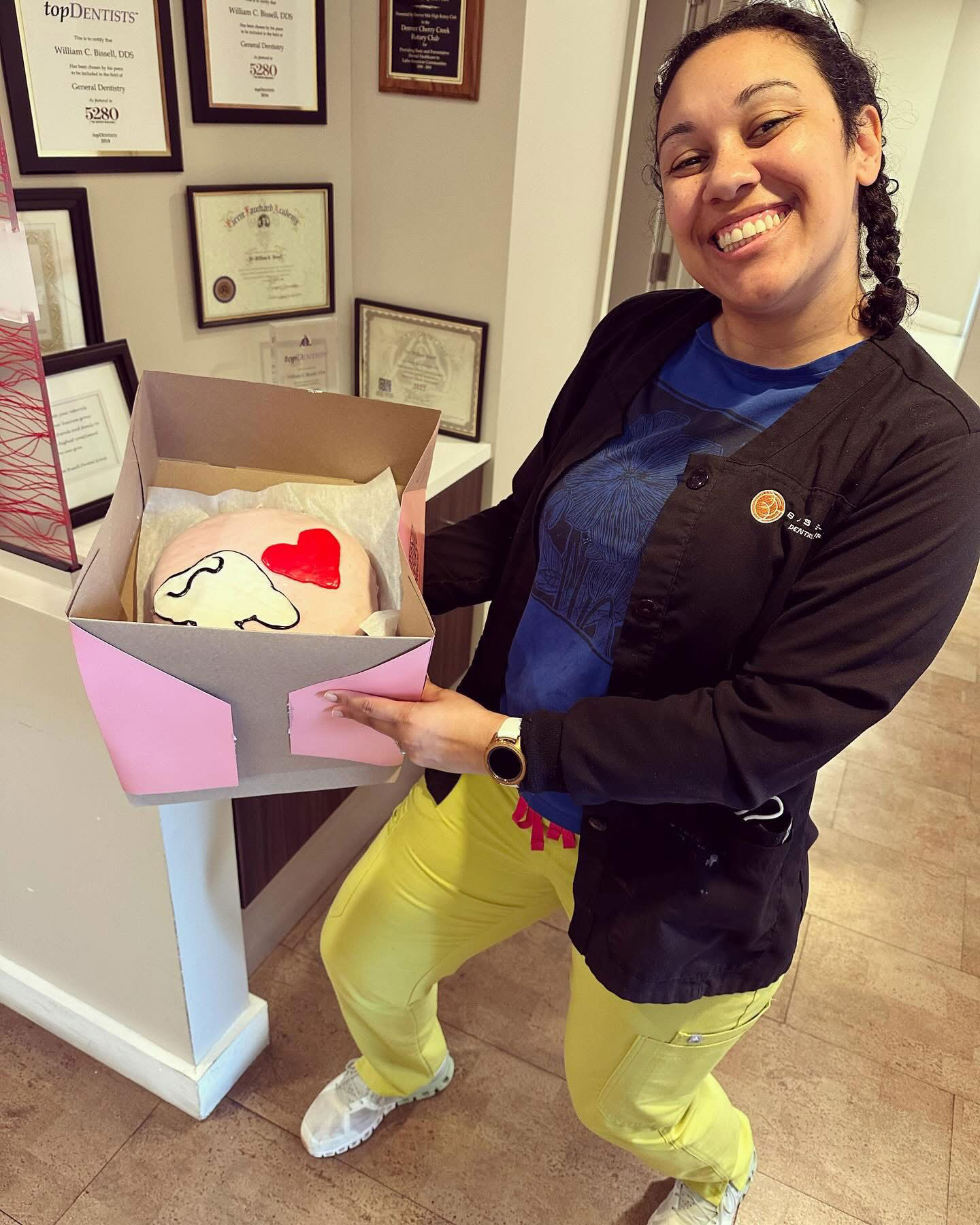 A woman holding a box containing a heart-shaped cake with a cartoon character on it.