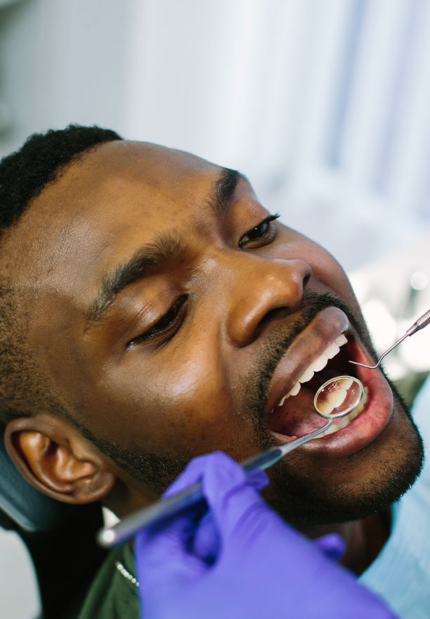 A man receiving dental treatment while seated in a chair.