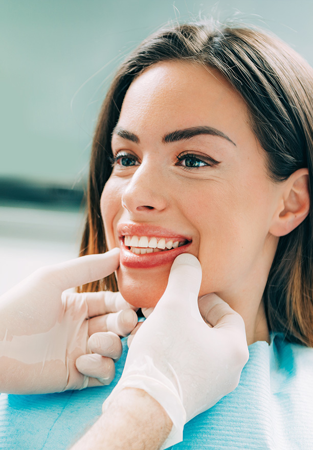 A woman receiving dental care while smiling at the camera.