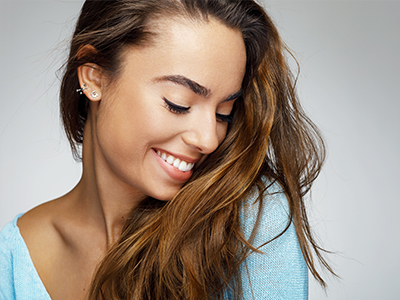 A young woman with long hair, smiling at the camera, against a plain background.