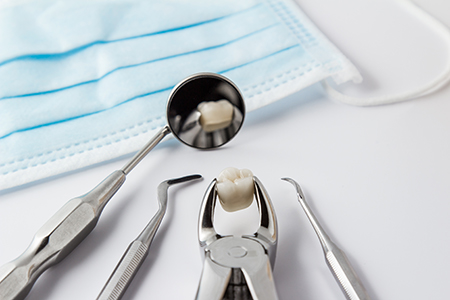 The image shows a dental tool set on a white surface with a blue surgical drape partially visible in the background, suggesting a medical or dental care context.