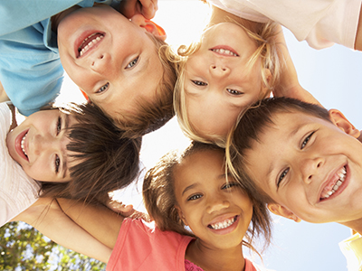 A group of children with smiles on their faces, posing together for a photo outdoors.