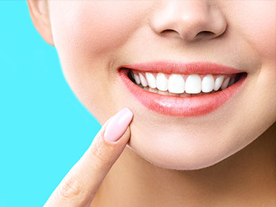 The image shows a close-up of a person with a bright smile revealing white teeth, against a blue background.